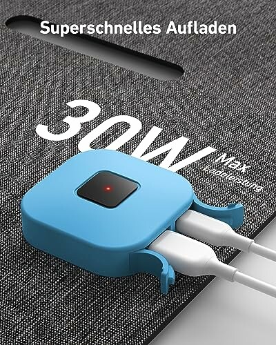 Blauer Ladeadapter mit zwei angeschlossenen Kabeln auf grauem Hintergrund.