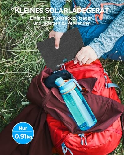 Person mit rotem Rucksack und Solarladegerät im Freien