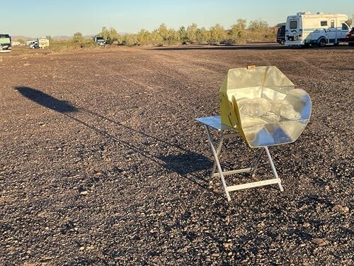 Ein Solarkocher steht auf einem Stuhl auf steinigem Boden.